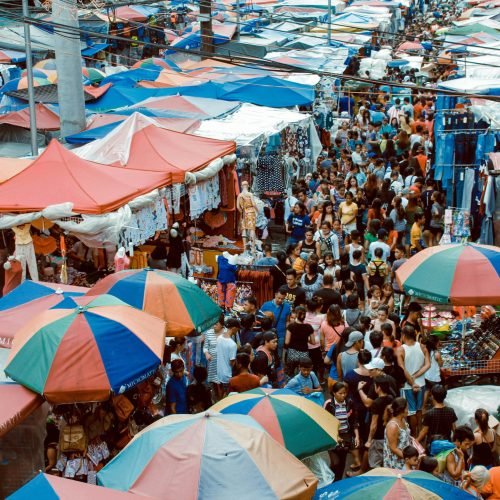 A bustling street market in Manila with colorful tents and a lively crowd shopping outdoors.